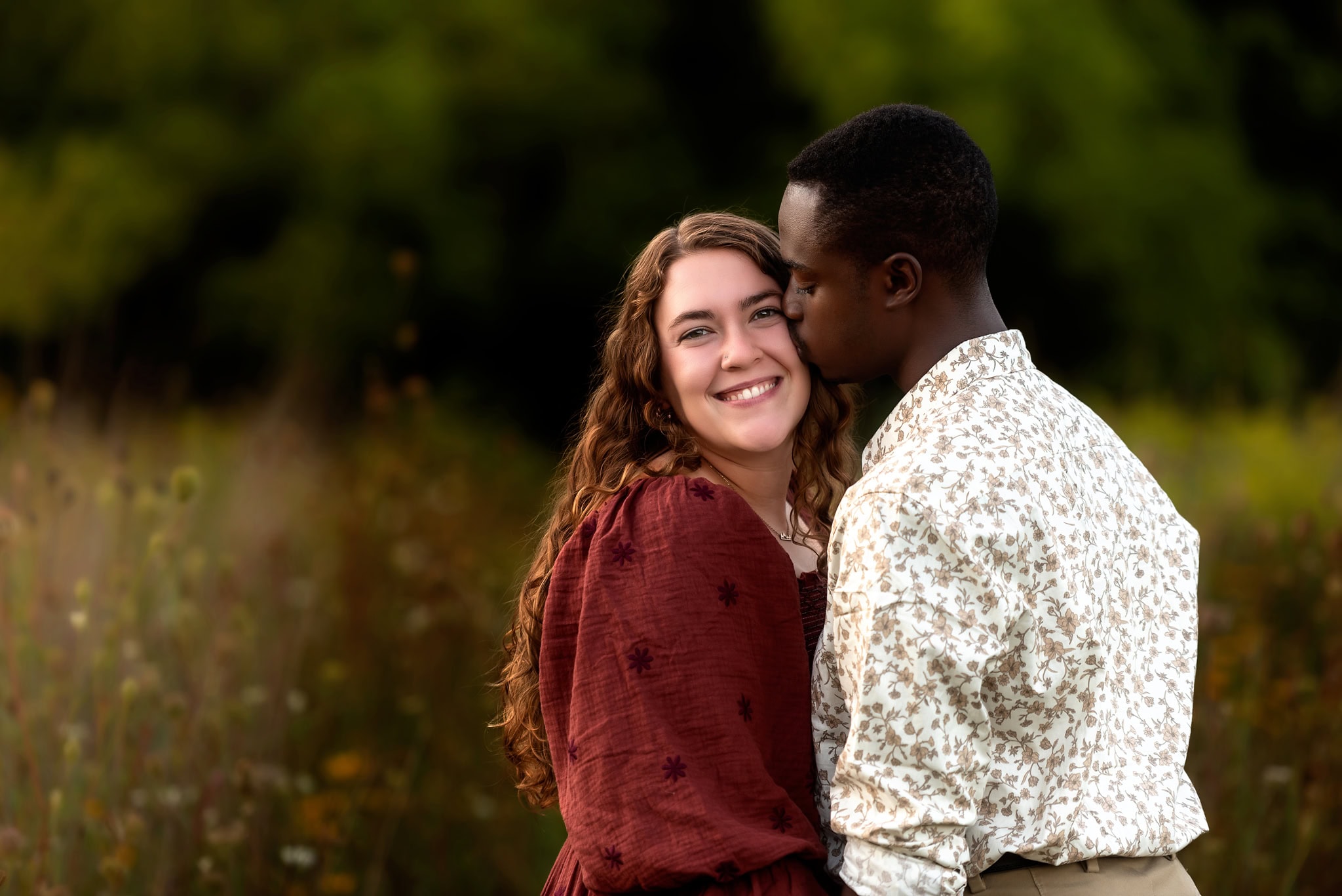 Metea County Park, Fort Wayne Engagement Photographer man kissing woman on cheek in flower field